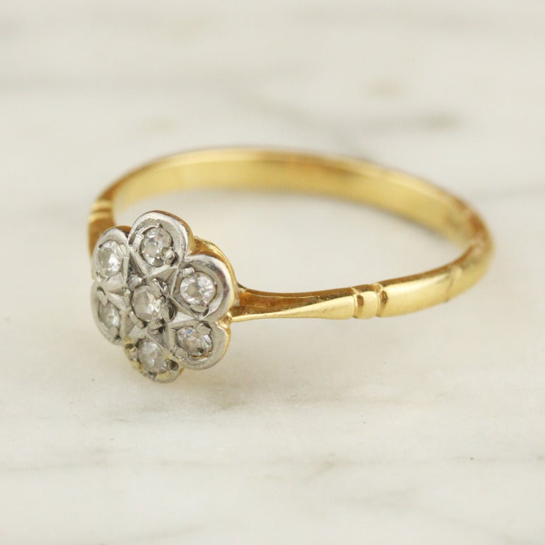 - Antique Diamond Flower Cluster Ring
- c. 1910-1925
- 18k yellow gold shank, platinum head, seven approximately .02 carat single-cut diamonds for a total weight of approximately .14 carats
- Made in England

A truly charming Edwardian diamond