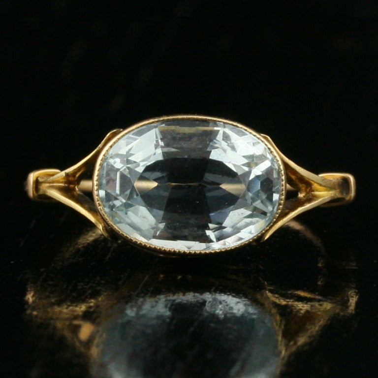 - Aquamarine Ring
- c. early-to-mid 20th century
- 18k yellow gold, one 2.23 carat oval brilliant aquamarine of light-toned, very slightly greenish blue

Aquamarine is rarely set in yellow gold, making this pretty split-shoulder 18k gold ring a