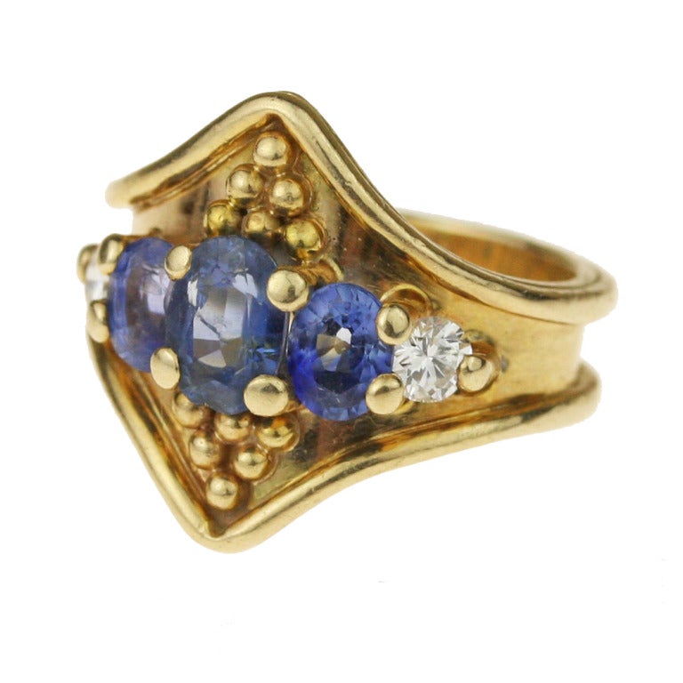 - Five Stone Panel Ring
- Handmade by our master goldsmith William L. Howard
- 14k yellow gold shank, 3 oval-cut sapphires with a combined weight of 1.89 carats, two round brilliant-cut diamonds with a combined weight of .26 carats, for a total