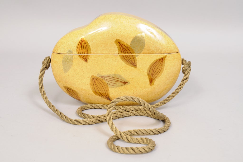 Beautifully crafted, this wooden purse is artfully painted and decorated with gold leaf. The shoulder strap is a woven gold cord. The bag is in excellent condition.

Measurements;
Height 5 1/2