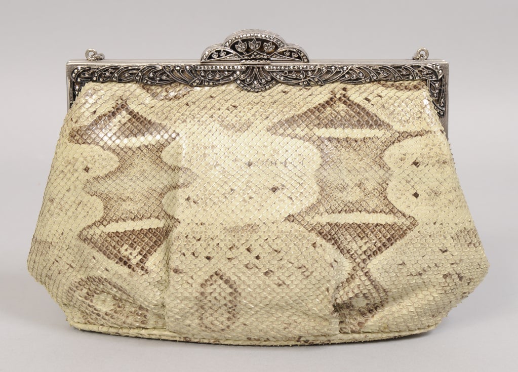 A gorgeous sparkling vintage marcasite frame is paired with a neutral snakeskin in this elegant evening bag created by Jacomo in the 1970's. The bag has a silver toned chain shoulder strap. It is fully lined in grey faille and it is in
excellent
