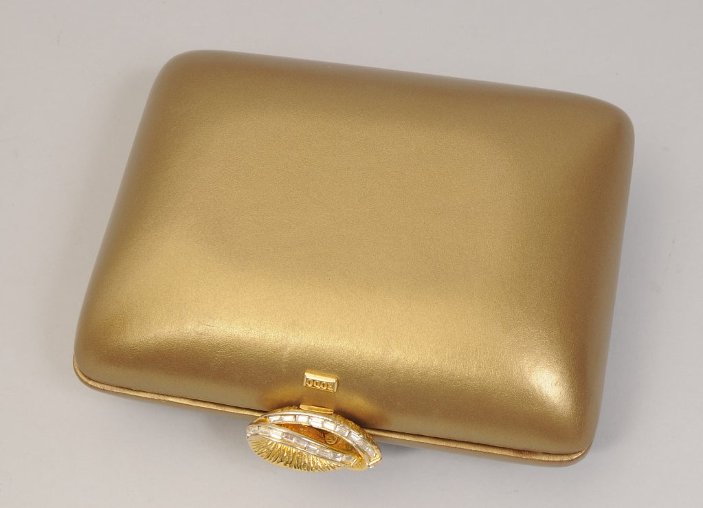 An unusual matte gold leather covers this rigid clutch bag designed by Rodo, with an optional chain strap tucked inside.
A diamante clasp and discreet Rodo logo are the only ornamentation. The interior is lined with a gold logo fabric and there is