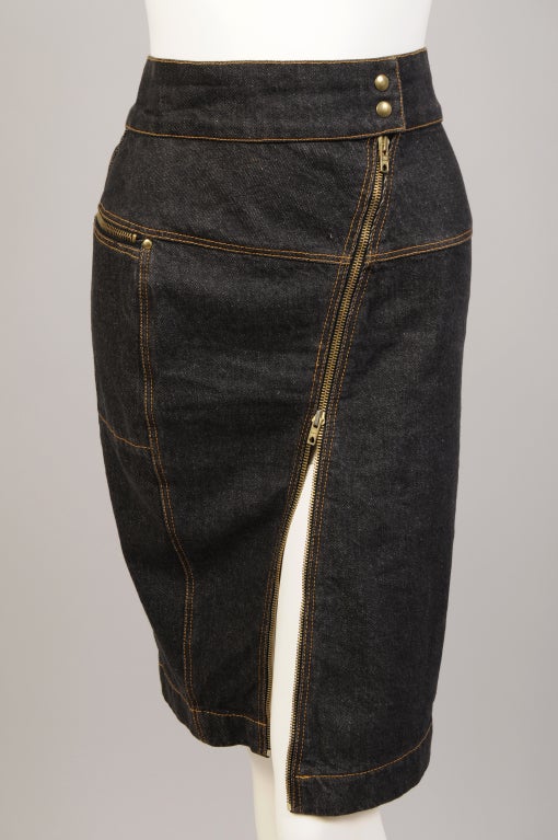 This Azzedine Alaia denim skirt has a sexy diagonal zipper at the front. There are two snaps at the center of the waistband. Two zippered pockets are the focal point of the back of the skirt which is cut and seamed for a very flattering fit. It is