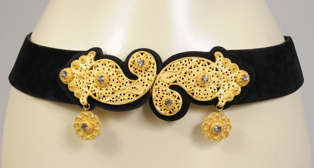 A gorgeous and adjustable black suede belt from Judith Lieber for Saks Fifth Avenue is decorated with a golden paisley shaped clasp. The suede belt can be adjusted from 24