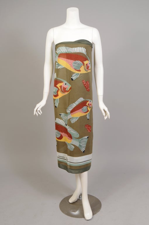 A school of tropical fish swim across this cotton scarf or pareo from Hermes, Paris. The background and borders are done in several shades of green and it is signed in the border. This charming piece has never been used and it is in excellent
