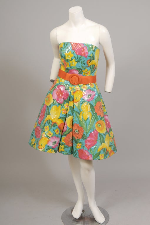 A gorgeous cotton floral print is covered with clear pailletes and accented with an orange silk belt in this strapless dress from Arnold Scassi. The dress is fully lined and has a tulle petticoat for extra fullness. It has a center back zipper and
