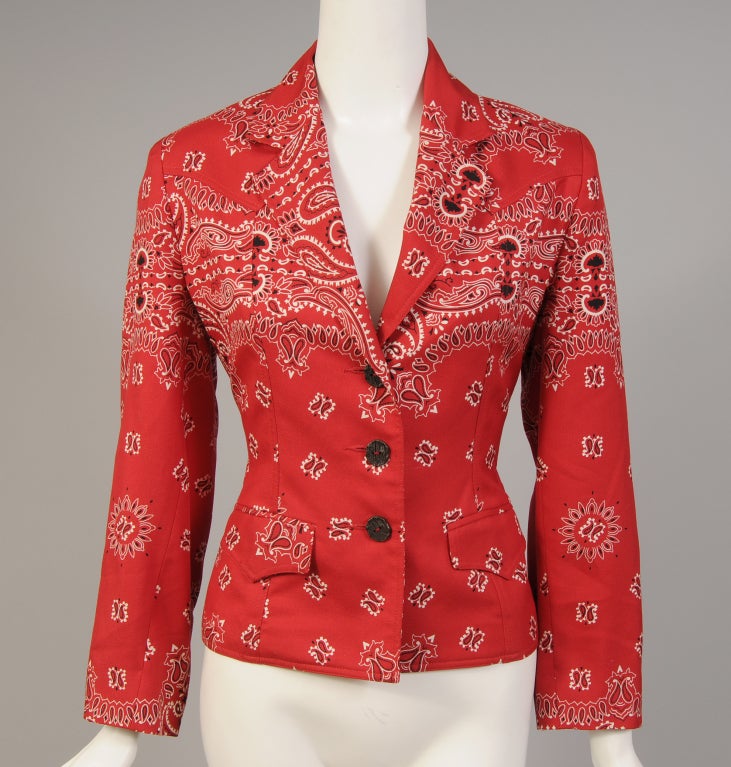 Todd Oldham uses a red and white bandana print in a silk twill for this charming Western cut jacket. It is fully lined in a matching silk print. There are metal buttons that look like wood grain at the center front and on each cuff. Marked a size 6