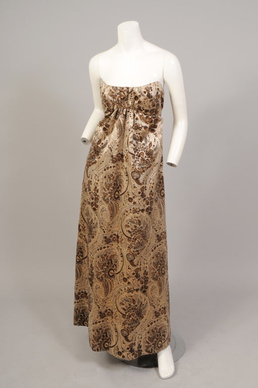 This is an exquisitely romantic and glamourous dress from Pauline Trigere designed in the 1960's. A luxurious woven and printed satin has a raised velvet pattern in shades of grey, beige and mocha on an ivory background. The strapless dress has an