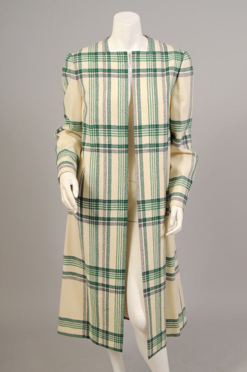 This light weight wool plaid coat was designed by Pauline Trigere for Bergdorf Goodman in the 1970's. It is a blanket plaid in black and green on cream wool. The coat slips on easily with no collar or closures. There are two pockets hidden in the
