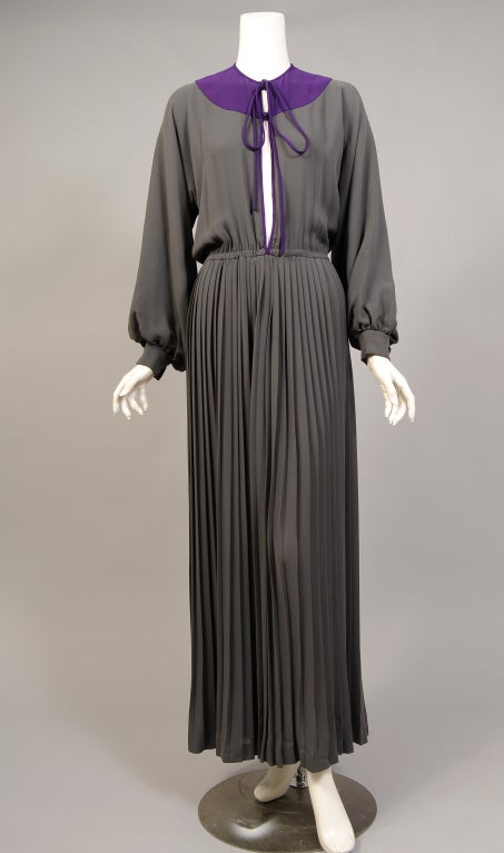 A regal purple yoke sets off this gorgeous grey silk dress from James Galanos designed in the 1970's. There is a purple cord tie at the neckline and a knotted purple button matching the purple buttons on the cuffs. There are concealed hooks and eyes