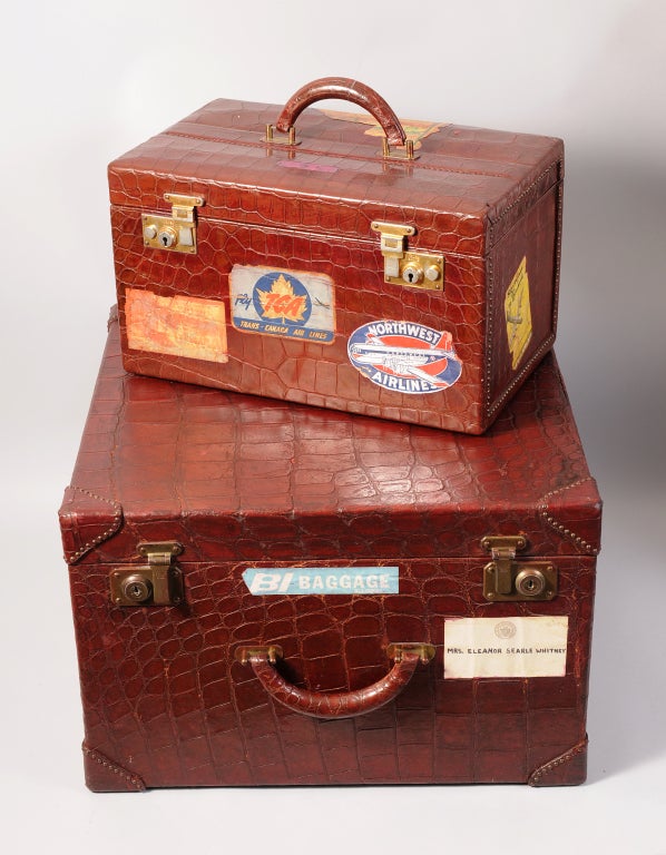 Two deep red/brown alligator suitcases, de-accessioned from a Museum in Mrs. Cornelius Vanderbilt Whitney's hometown, bear her name and numerous travel stickers.
The smaller cosmetic case is made by Mark Cross in England. The origianl stand up