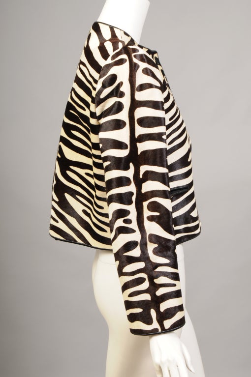 A Zebra pattern is stenciled in brown and white on this short and chic calfskin jacket from Bill Blass. The jacket is trimmed with brown leather piping and closes with three brown buttons. There are two leather trimmed pockets and it is fully lined