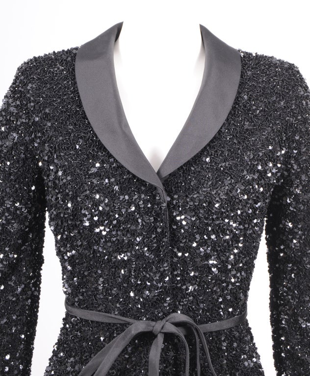 Badgley Mischka has designed a stunningly fresh and modern version of the classic ladies dinner jacket. The black satin lapels are narrow, as is the flat tie belt at the waistline. The jacket is made from a layer of fine black tulle smothered in six
