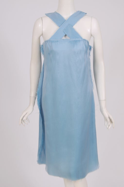 A gorgeous shade of blue silk is finished in an unfinished manner by the Mulleavy sisters of Rodarte. The criss cross straps have been edged with a pinking scissors to match the bustline and the curved hem. The side seams are left raw and self