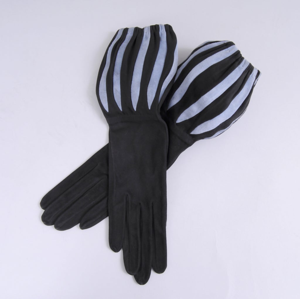 Black and blue suede is combined in these great 1950's gloves retailed by Bloomingdale's. The cuff can be worn in two ways, either pulled up on your arm for an elegant look or pushed down to create a dramatic balloon look. They are marked a size 7,