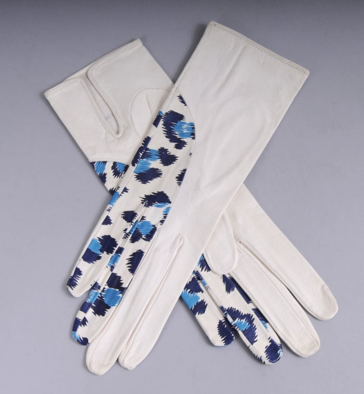 Made from two different leathers these French gloves are quite charming. The body of the glove and three fingers are a creamy white leather. The ring finger and pinky are made from another leather with a stylized leopard spot in two shades of blue.