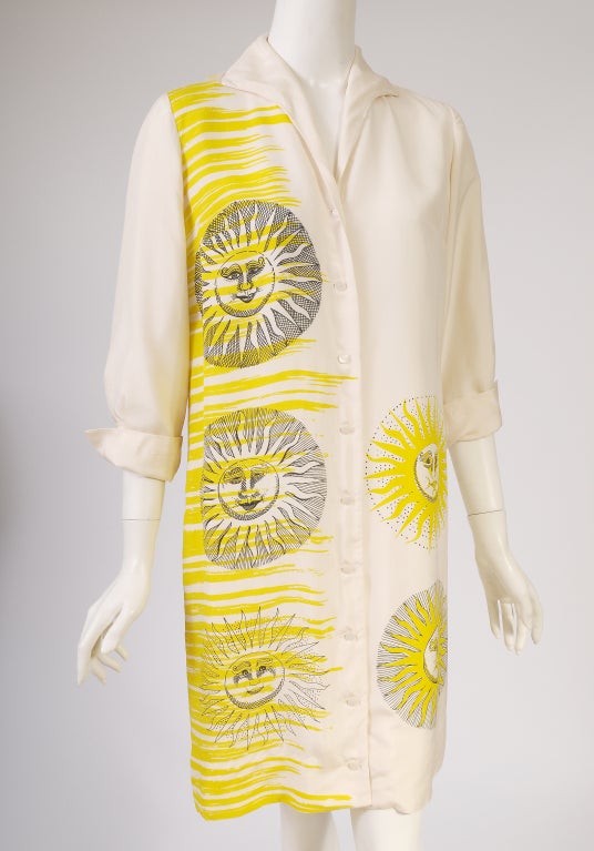 Rich cream colored silk is printed with Fornasetti inspired sun faces in a bright lemon yellow with black accents. Five different variations of the face are on the front of the dress and there is one large sun face on the back.  The dress buttons