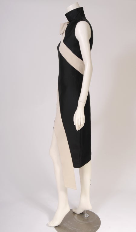 A stunning and simple black silk gazar dress is trimmed with a cream colored sash starting on the right shoulder and wrapping around the body. It ends below the hem on the left side of the center. It makes me think of a fallen beauty queen! The