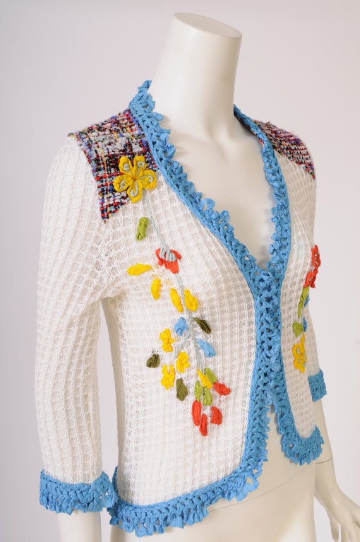 Bright blue crocheted trim edges this white cotton sweater from Christian Lacroix. There is a colorful floral embroidery on the front and a tweed yoke on the front and back. It is in  excellent condition.

Measurements;
Shoulders 15