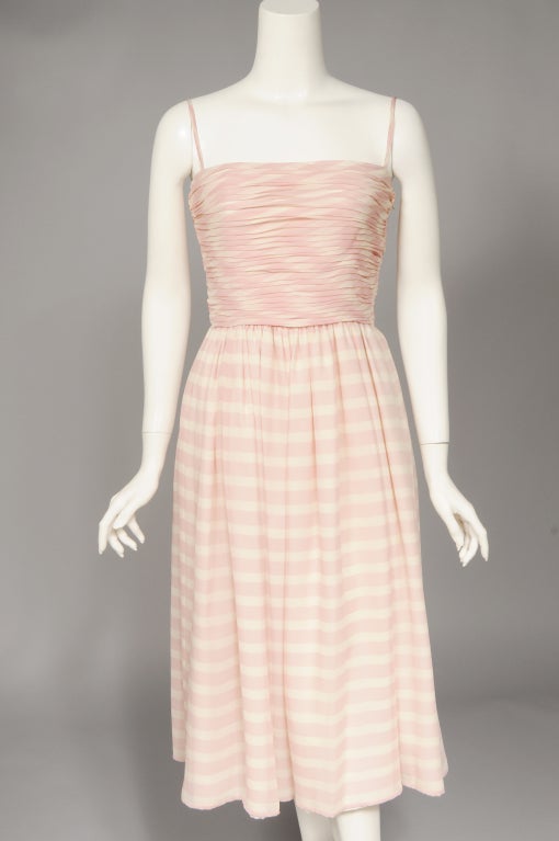 Pink and white striped silk is pleated at the bodice of this dress. The full skirt is gently gathered at the waist line and it is lined in cream silk. A matching scarf comes with the dress. Both pieces are in excellent condition and the dress is