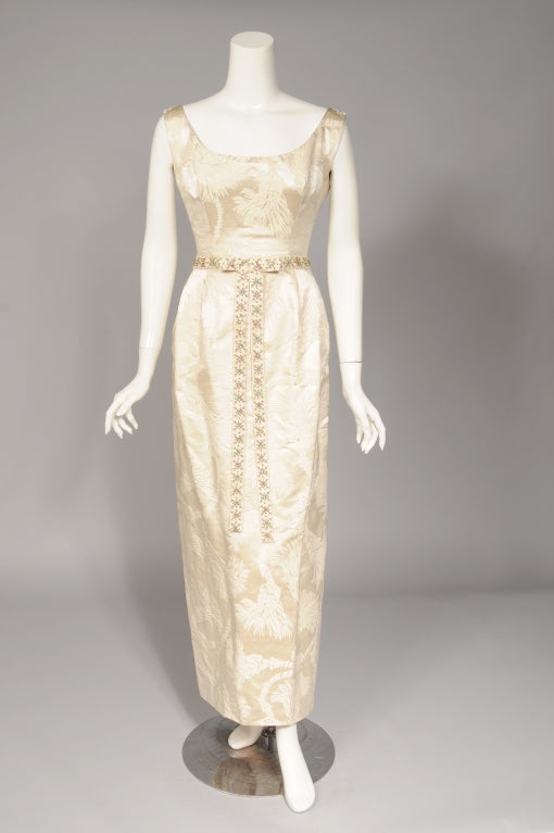 This is a beautifully designed and constructed evening dress and coat made by Nitsa in Athens, Greece in the late 1950's. Both pieces are made from a creamy woven damask with a very chic cord and tassel design. The sleeveless gown has a scoop