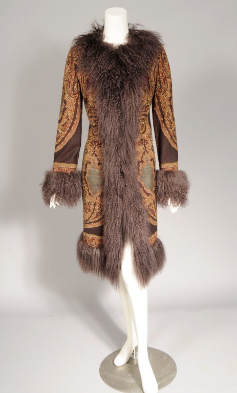 A striking wool paisley coat in shades of gold, orange, burgundy and tan on a deep chocolate brown background is enhanced by brown Mongolian lamb fur trim. The coat is fully lined in a blend of wool and cashmere in a soft camel color. It closes with