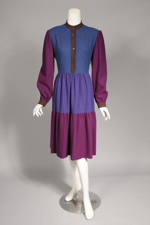 This 1970's color block dress is made from a soft wool blend in teal blue, and two shades of purple. The band collar, button front and cuffs are done in brown wool. Two pockets are concealed in the side seams. The dress was retailed by Bergdorf