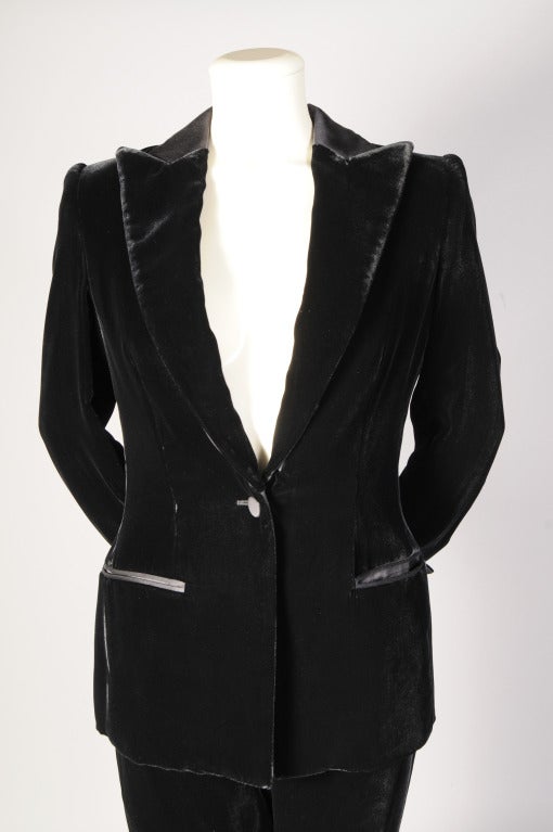 A pristine Giorgio Armani black velvet tuxedo is trimmed with black satin on the collar, cuffs and pockets as well as the single button closure. The flat front trousers have a satin stripe on the side of the pant legs. Both pieces are in excellent