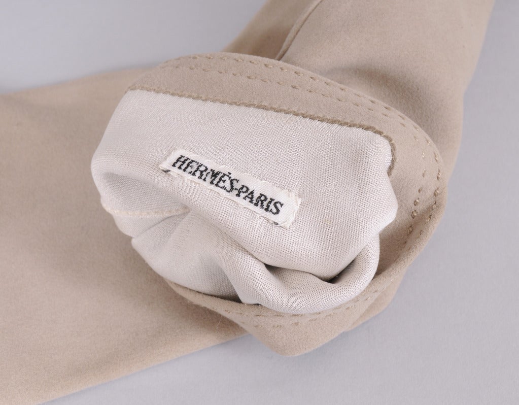 Taupe suede gloves are lined in silk and finished with a duble row of stitching at the cuffs. They have never been worn and they are marked a size 6 1/2. Your glove size is usually the same as your shoe size.