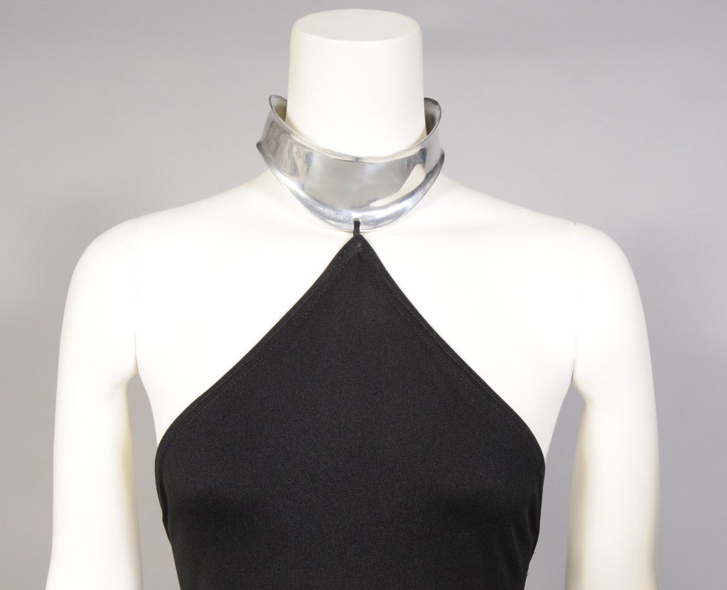 A collaboration between famed clothing designer Rudi Gernreich and jeweler Chris den Blaker resulted in a small group of evening dresses with attached aluminum jewelry. This dress from the mid 1970's is a black crepe halter dress with a deep left