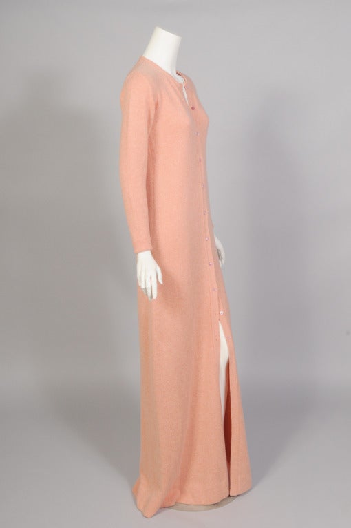 An iconic piece from Halston, this floor length melon colored cashmere cardigan dress is made from Scottish cashmere and it is so soft to the touch. It buttons down the front with a series of pearl buttons. Wear it with your Elsa Peretti silver