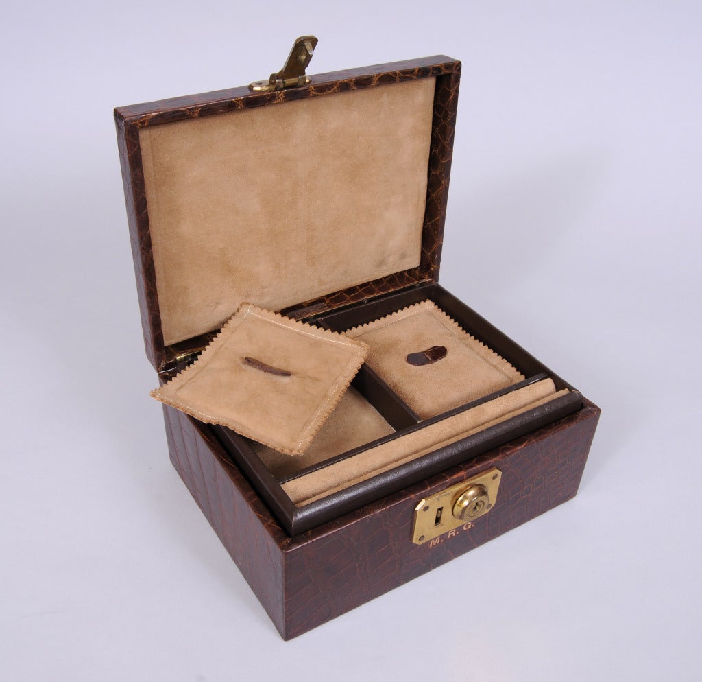 Rich brown alligator covers the outside of this 1950's jewelry box from Abercrombie & Fitch, New York. The box has a suede lining and a removable tray, This tray has a place for rings and two suede lined compartments with suede pillows for added