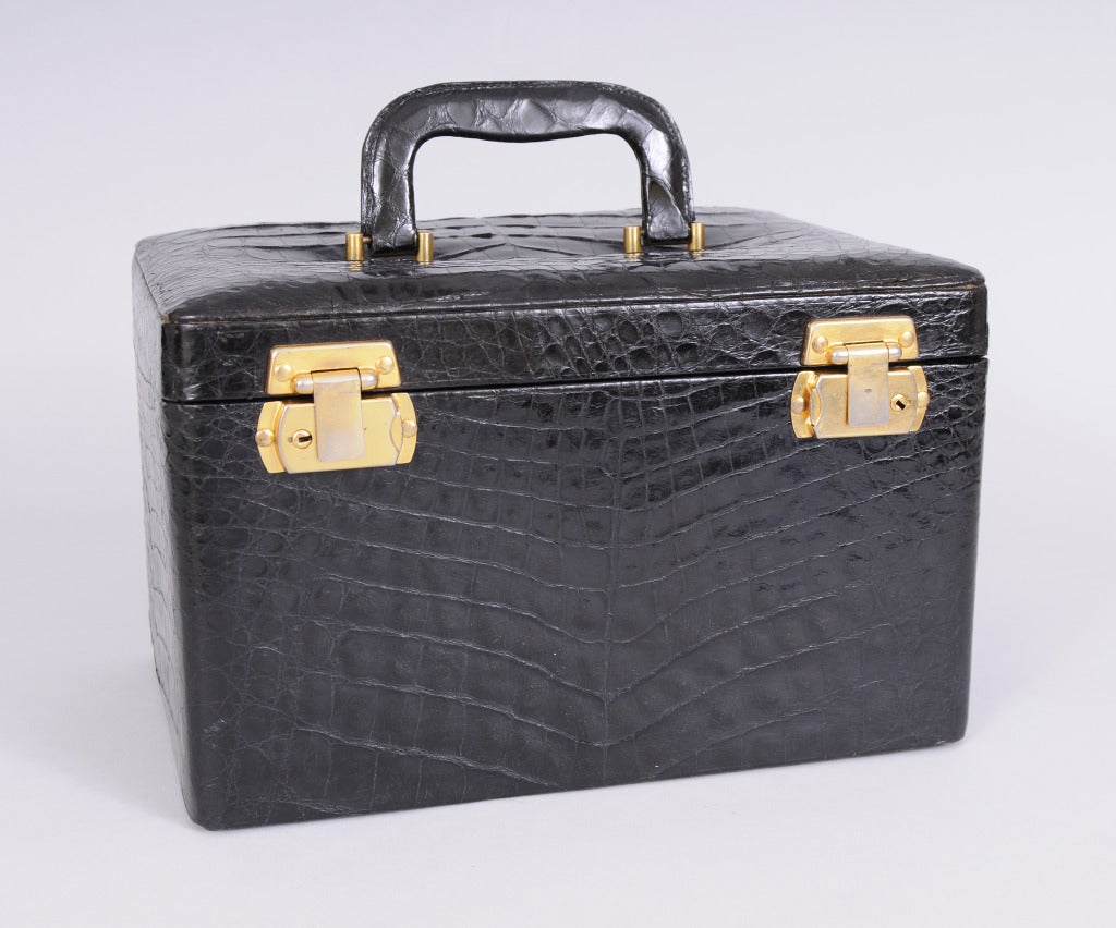 This sleek black crocodile travel case, made in Argentina, has a mirror in the top, a removable crocodile jewelry box and space for toiletries below. The velvet lined jewelry box has three compartments with crocodile covers and two slotted