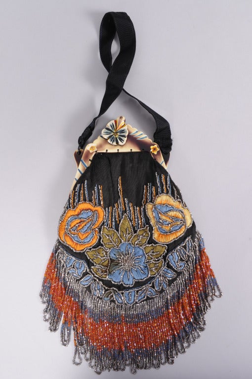 From a Beverly Hills collector, this black silk bag is hand embroidered and beaded with cut steel beads in a combination of floral and geometric designs. A striking celluloid frame repeats the floral motif and balances the long multi-color beaded
