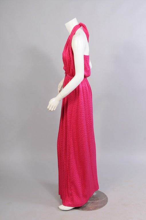 This stunning halter dress from James Galanos  in a tone on tone cyclamen silk is left open to the waistline for a very sexy 1970's look. The skirt has a pleated center front, concealing a zipper and hook and eye closure. The back dips low for added