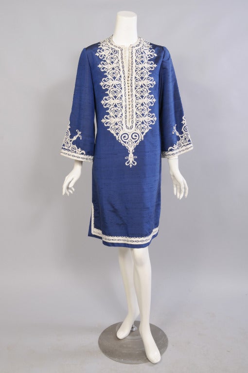 A beautiful deep blue silk is lavishly trimmed with white silk braid. The neckline has a long row of buttons and loops and a generous amount of hand appliqued trim. Braid runs down the center of the sleeve to a matching set of buttons and more
