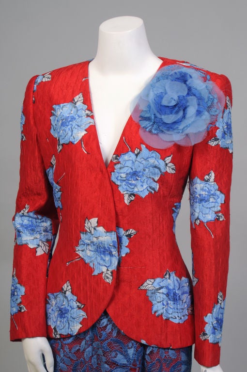 Gorgeous colors and great fabrics make this evening suit from James Galanos a standout in the usual sea of black dresses. The collarless jacket is made from a printed, quilted silk and embellished with an oversized silk and lace flower on the left