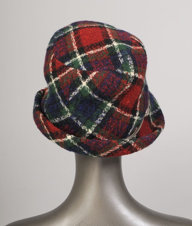 Yves Saint Laurent designed a very stylish hat from a chic nubby wool plaid.  The brim is trimmed with an elegant silver tone triple chain hatband with five oval medallions and two silver tassels. It is fully lined and in excellent condition.<br