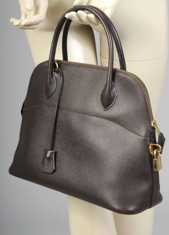 A chocolate brown Hermes Bolide bag in pristine condition has a top zipper, lock and key clochette as well as two shoulder straps.  A wide leather trimmed canvas strap and a matching narrow leather shoulder strap are included with this bag.  In