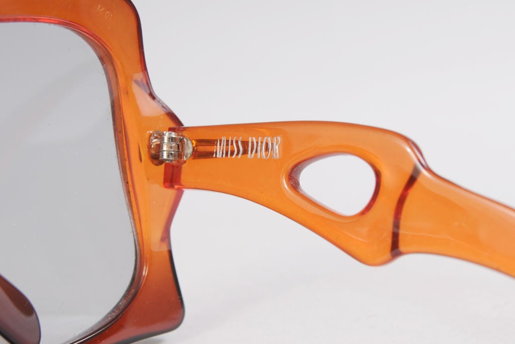 Outrageously oversized sunglasses from Miss Dior were made in France in the late 1960's. The clear plastic frames are a warm rust/orange color with tear drop openings on the sides. They are in excellent condition.<br />
<br />
Measurements;<br