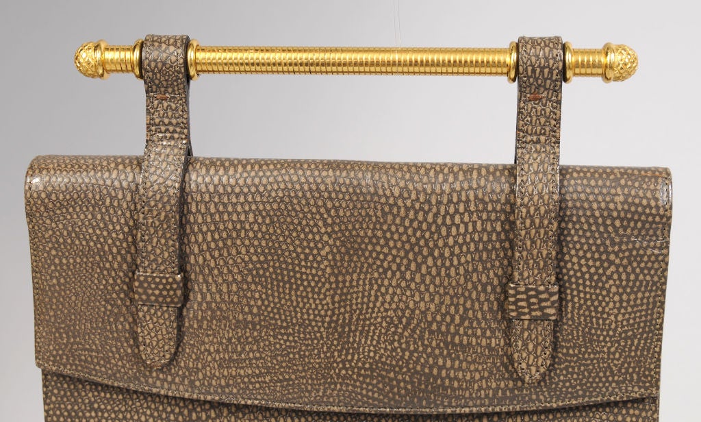 A striking and unusual design from Bienen-Davis is done in a textured leather with a wonderful golden handle across the top.<br />
This bag can be carried as a clutch or a handbag and it works perfectly for day and/or evening.  The bag is lined in