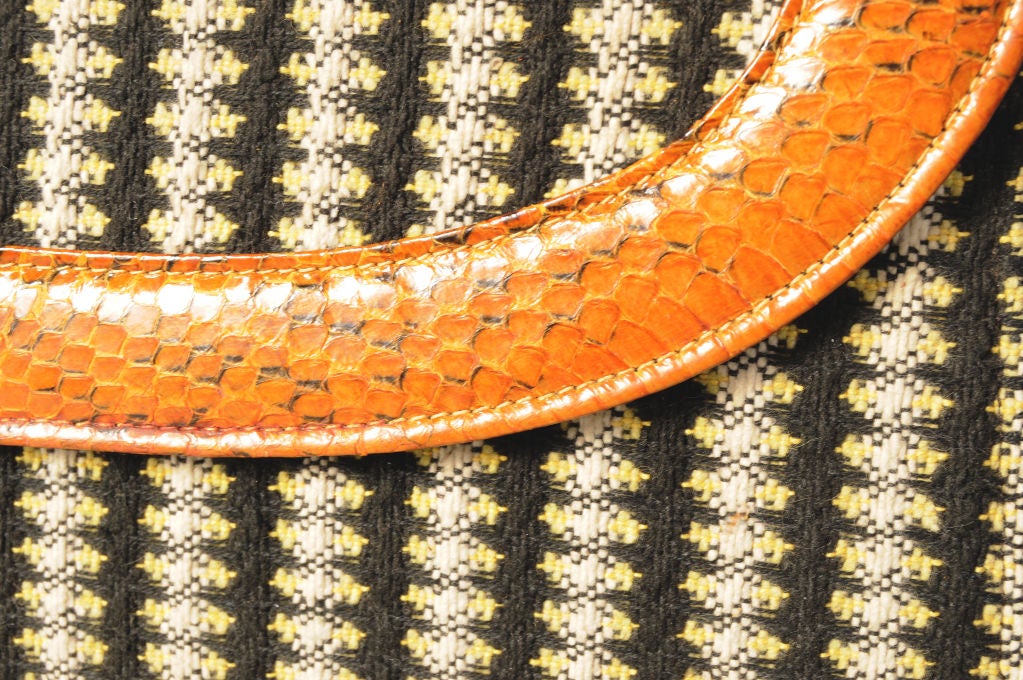 Rich caramel brown snakeskin is used as an accent on the opening flap and two front corners of this 1930's fabric covered clutch bag. The bag is lined in black fabric and it has a zippered compartment as well as an open pocket.  It is marked Deitsch