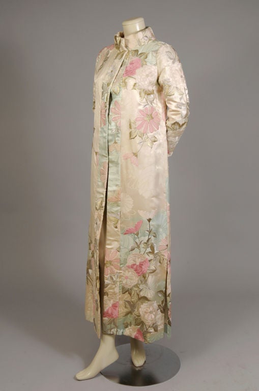 This exquisite Japanese coat or coat dress, made for the Western market, is lavishly embroidered on a beautiful woven silk damask.  The silk background is woven with a tone on tone floral pattern, and shaded with an ombre sky blue. The pastel