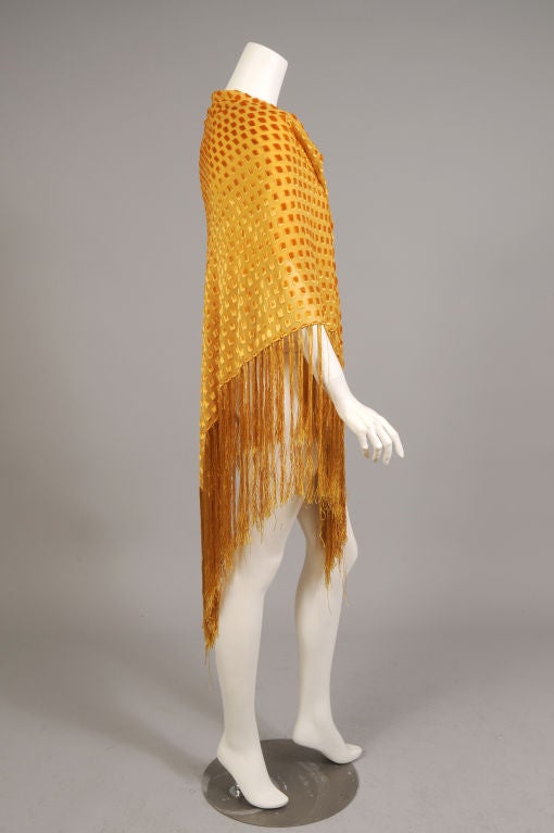 A gorgeous saffron colored voided velvet on silk chiffon is used for this shawl from the 1980's. Made in Paris, it is reminiscent of the Art Deco shawls from the 1920's, but it is so much more wearable. The shawl is edged with matching silk fringe
