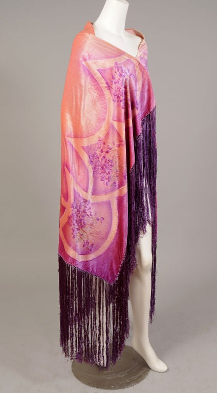 An art deco silk velvet shawl is hand painted in ombred shades of pale pink to deep violet. Bouquets are stenciled in a deep violet with silver leaves and stems., and centered in pale pink semi-circles. The shawl is edged on three sides with<br