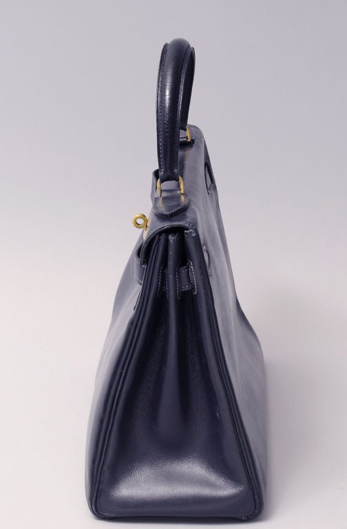 This navy blue box calf leather Hermes Kelly bag with gold toned hardware is truly vintage. The blind satmp dates it to 1957! It is in excellent vintage condition with wear commensurate with age. The photos have been lightened to show the actual