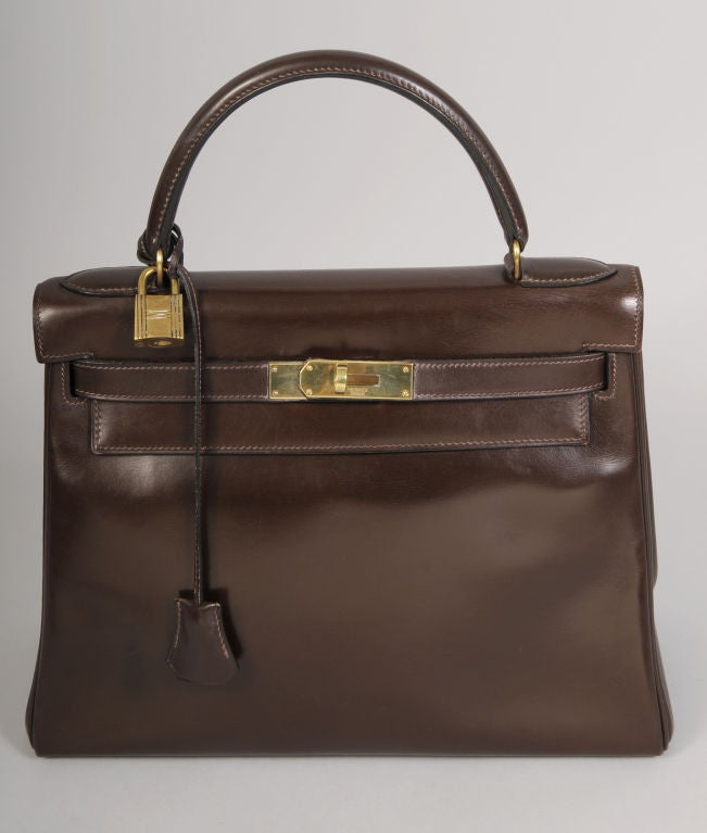 Deep, rich brown box calf leather is accented with mellow gold hardware in this 28cm Kelly bag from Hermes. It was created in<br />
1961 and retailed by Bonwit Teller before Hermes had shops in the United States. The bag was seldom used by the