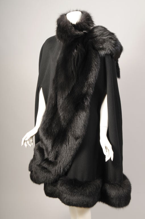 This gorgeous Fendi wrap was retailed by Henri Bendel. Rich and luxurious black fox fur trims all of the edges of the cape, and a wide piece trimmed with fur tails sits perfectly on your shoulder. There is an interior button and buttonhole at the