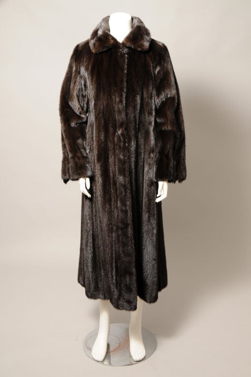 Dark, dark brown ranch mink, called Black Willow, is used for this elegant mink coat from the late 20th century. Fur hooks line the front so you can get as much warmth as you desire. The long sleeves are adorned with mink tails for a bit of whimsy.