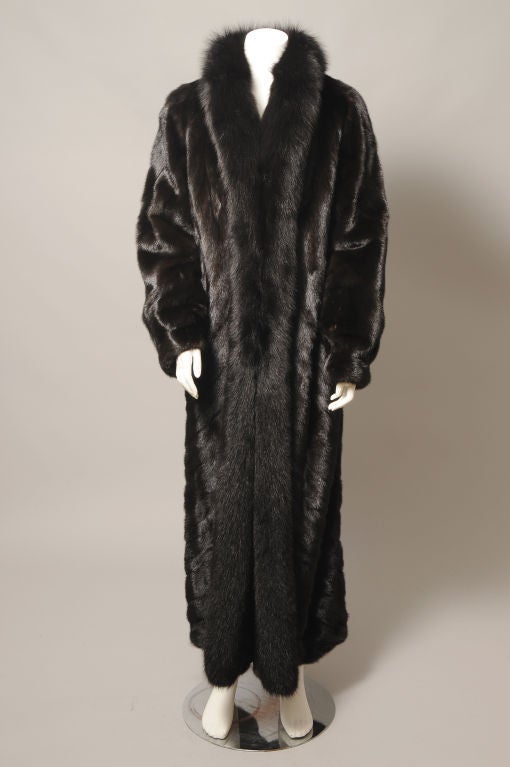 A fabulous full length ranch mink in a larger size is a great find. This one is in pristine condition and appears unworn. The pelts are worked on the diagonal, an elegant and flattering touch. The coat is lavishly trimmed with rich black fox,